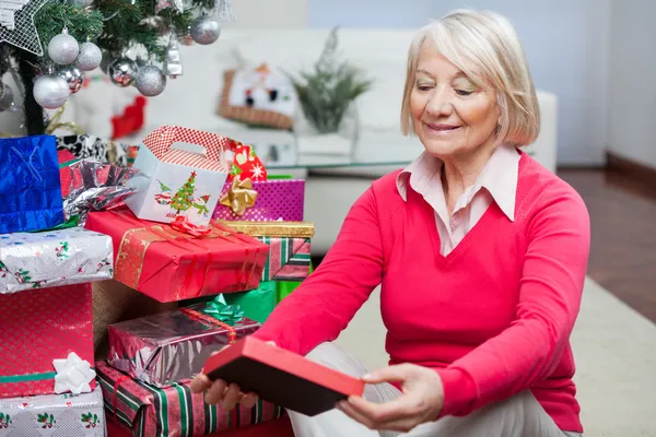 Senior Woman Looking At Christmas Gift — Stock Photo, Image