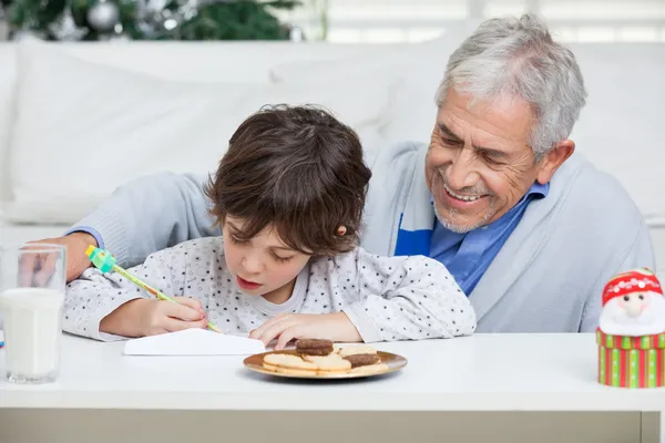 Grootvader meewerkende jongen in het schrijven van de brief aan de Kerstman — Stockfoto