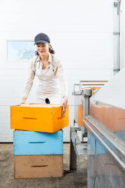 Apicultor con cajas apiladas de panal trabajando en fábrica —  Fotos de Stock