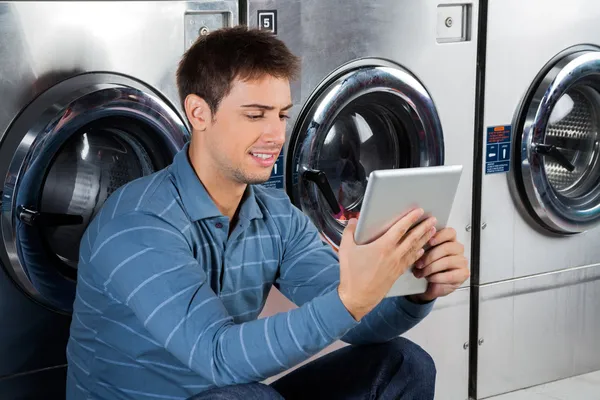 Homem usando tablet digital na lavanderia — Fotografia de Stock