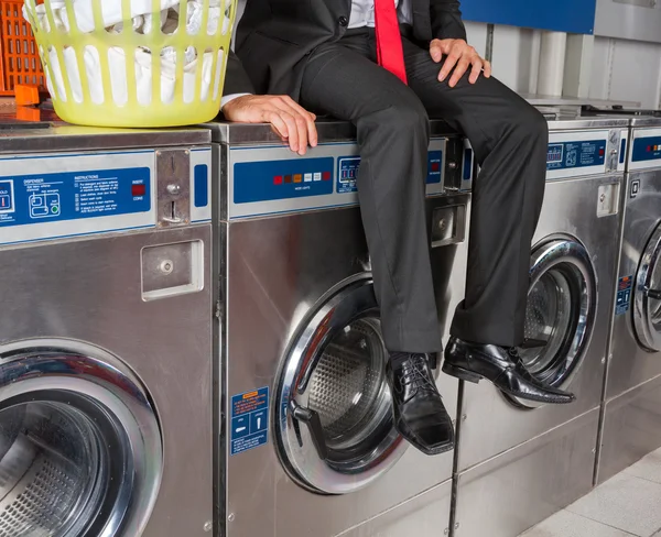 Empresário sentado na máquina de lavar roupa — Fotografia de Stock