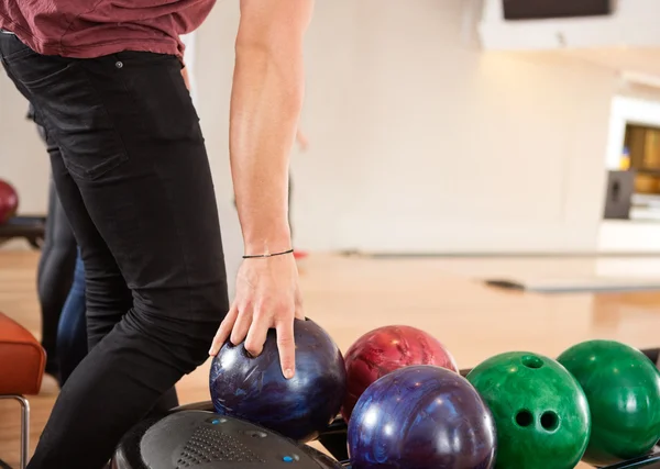 Jonge man kiezen bowling bal uit rek — Stockfoto