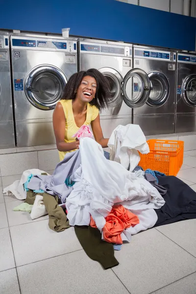 Mujer sentada con ropa en el piso en la lavandería —  Fotos de Stock