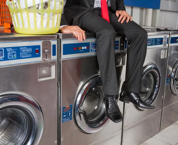 Businessman Sitting On Washing Machine Stock Photo