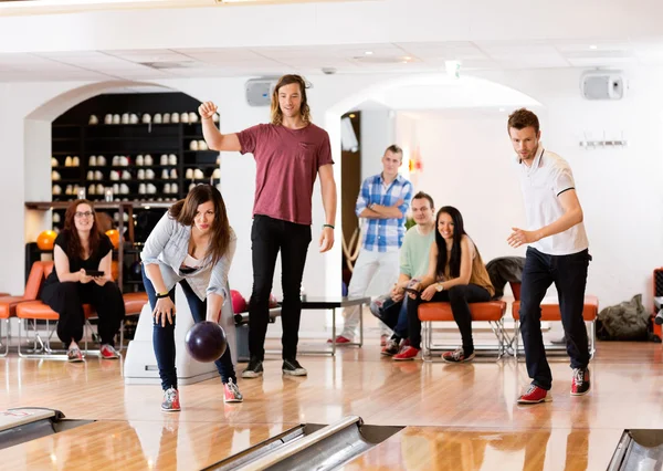 Muž a žena, bowling s přáteli v pozadí — Stock fotografie