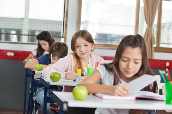 坐在办公桌前和同学们一起在一排的女生 — 图库照片