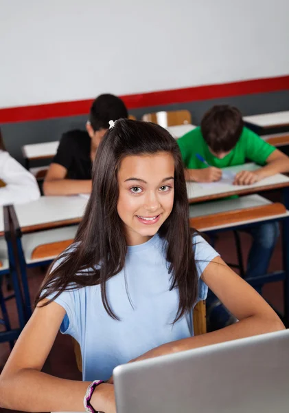 Gelukkig tiener schoolmeisje zitten met laptop aan balie — Stockfoto
