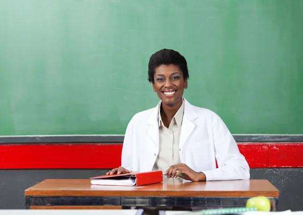 Porträt eines glücklichen Lehrers am Schreibtisch im Klassenzimmer — Stockfoto