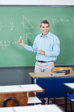 Male Teacher Teaching Mathematics On Board clipart