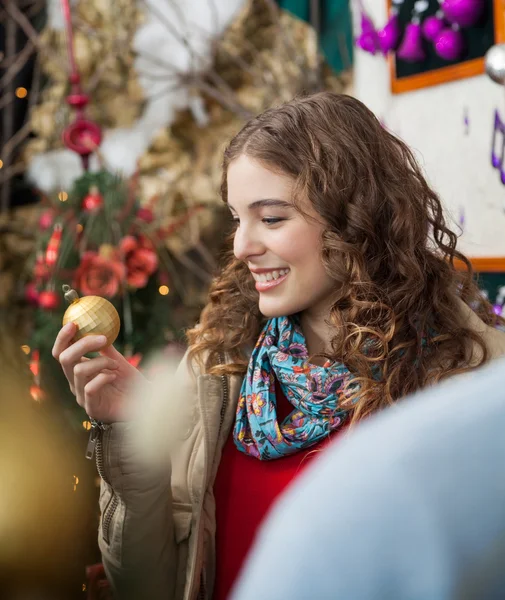 Frau blickt auf goldene Christbaumkugel im Geschäft — Stockfoto