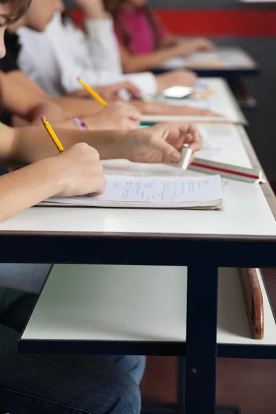 Schüler schreiben hintereinander am Schreibtisch im Klassenzimmer — Stockfoto