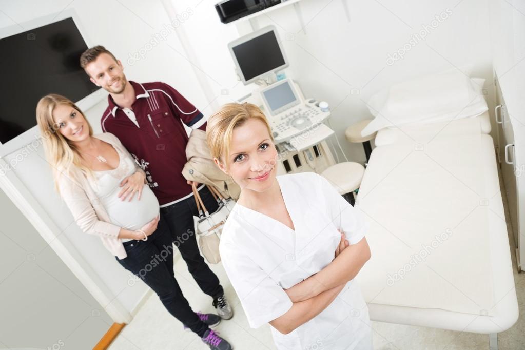 Doctor And Expectant Couple In Examination Room
