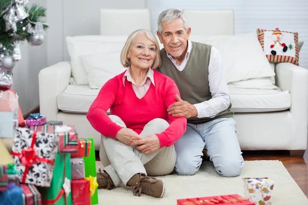 Felice coppia anziana seduta da regali di Natale — Foto Stock