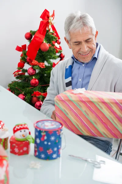 Man Looking At Wrapped Christmas Present — Stock Photo, Image