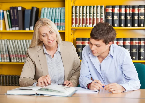 Teacher Explaining Student While Sitting At Table In Library — Stock Photo, Image