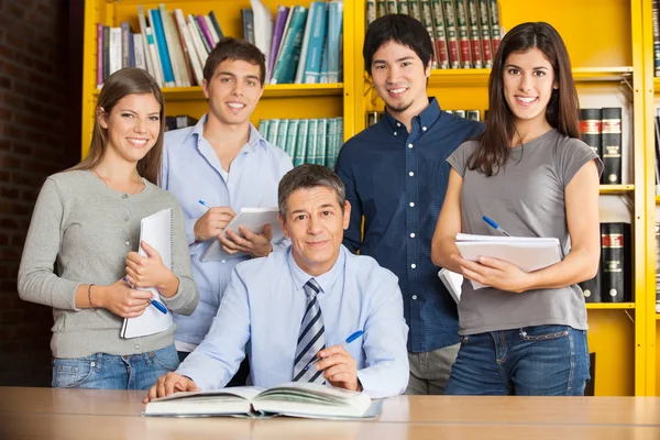 Bibliotecario fiducioso con gli studenti nella biblioteca del college — Foto Stock