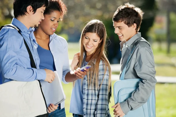 Student visar mobiltelefon till klasskamrater i college campus — Stockfoto