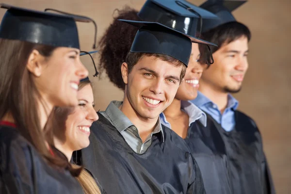 Glad man med studenter på graduation dagen i college — Stockfoto