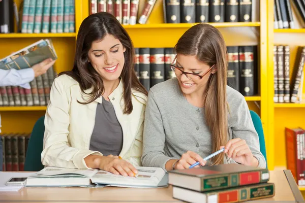 Amigos estudiando en la mesa en la biblioteca —  Fotos de Stock