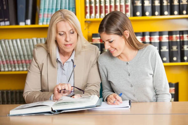 Leraar uitleggen student in college bibliotheek — Stockfoto