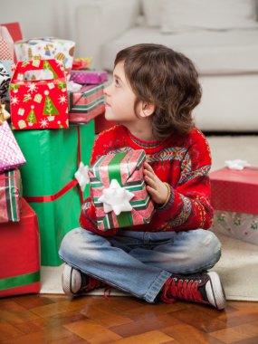 katta otururken Noel hediyesi tutan çocuk
