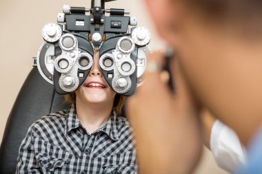 göz testi phoropter ile geçiren çocuk