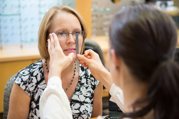 Vrouwelijke opticien meten vrouw brillen — Stockfoto