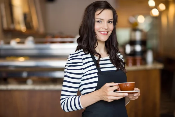 Красивая официантка держит чашку кофе в кафе — стоковое фото