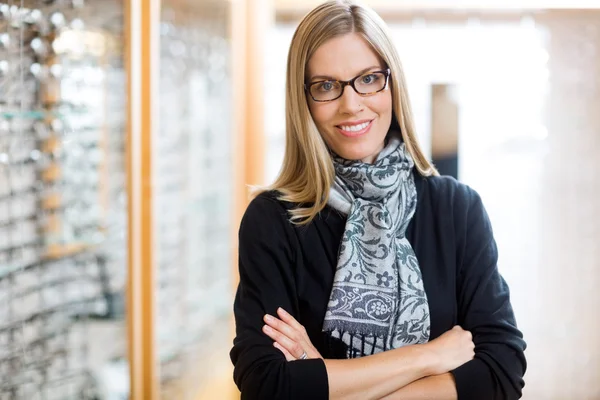 Vrouw dragen van een bril met armen gekruist in winkel — Stockfoto