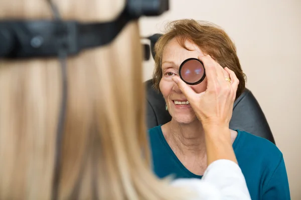 Óptica Examinando el ojo de la mujer mayor — Foto de Stock