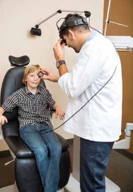 Optician Examining Boy's Eye Through Lens clipart