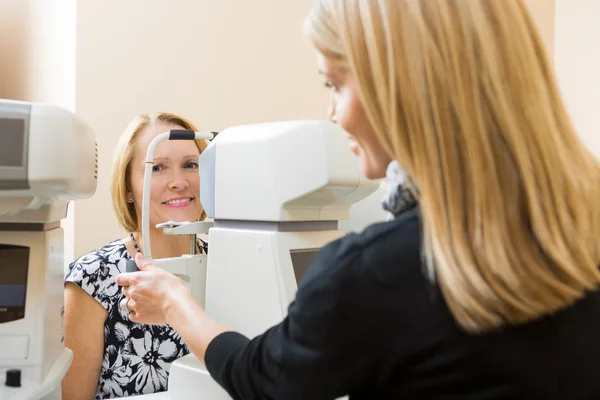 Оптометрист, использующий тонометр для измерения давления глаз пациентов — стоковое фото