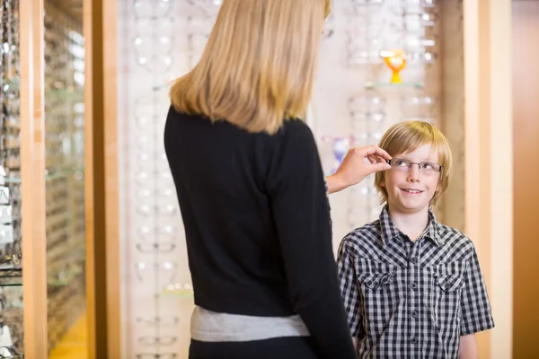 Mutter probiert Brille an Sohn im Geschäft aus — Stockfoto