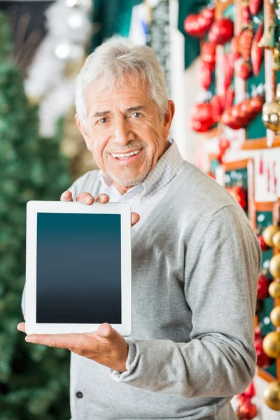 Homme affichant la tablette numérique dans le magasin de Noël — Photo