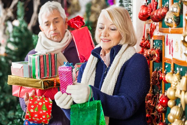 Feliz mulher compras presentes com o homem cansado — Fotografia de Stock