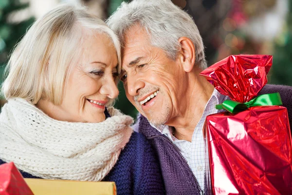 Pareja cariñosa con regalos de Navidad en la tienda — Foto de Stock