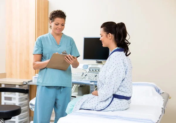 Nurse Writing Notes With Patient Sitting On Bed — Stock Photo, Image