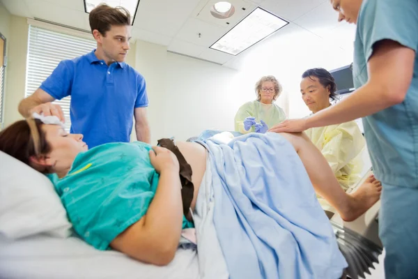 Uomo guardando squadra medica operante donna incinta — Foto Stock