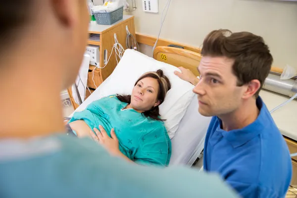 Mujer embarazada y marido mirando enfermera en el hospital — Foto de Stock