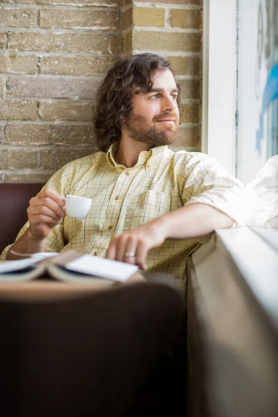 Man met koffiekopje kijken via venster in café — Stockfoto