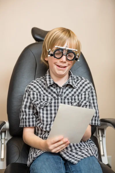 Jongen met proef frame lezen testkaart op stoel — Stockfoto