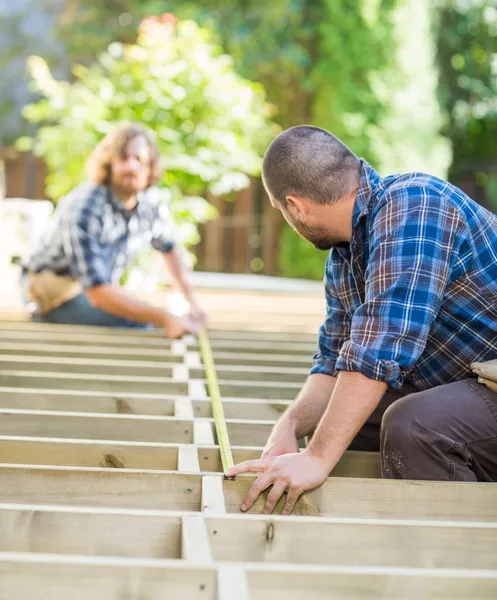 Timmerlieden meten van hout met tape op site — Stockfoto