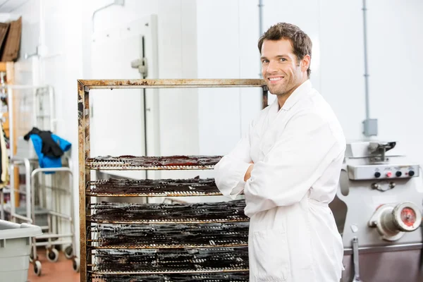 Trabajador de confianza de pie por el bastidor de carne de res Jerky en la tienda —  Fotos de Stock