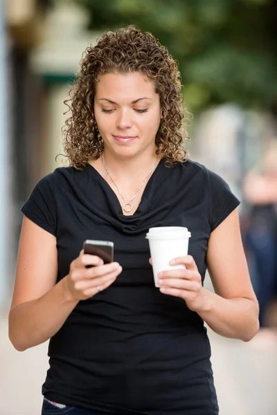 スマート フォンでのメッセージングのコーヒー カップを持つ女性 — ストック写真