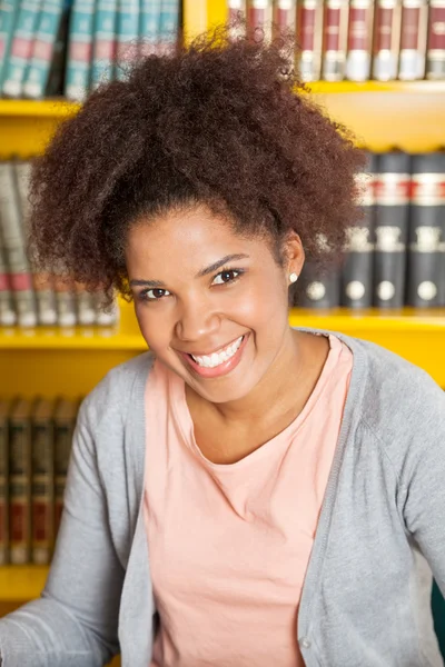 Estudante bonito sorrindo na biblioteca da universidade — Fotografia de Stock