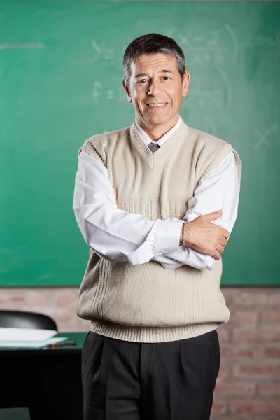 Professor stående armar korsade i klassrummet — Stockfoto