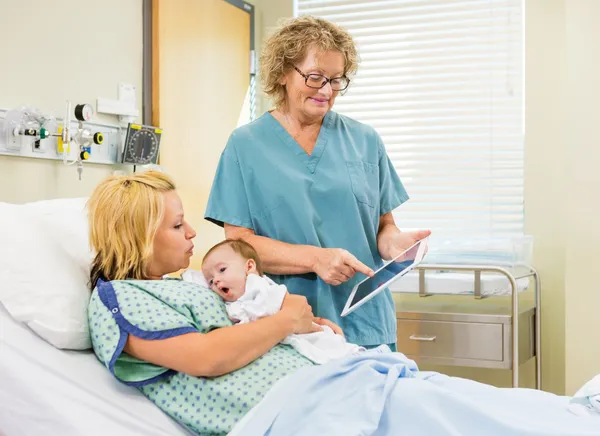 Krankenschwester erklärt Frau mit Baby Berichte über digitales Tablet — Stockfoto