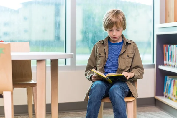 Çocuk kütüphanede kitap okuyor. — Stok fotoğraf