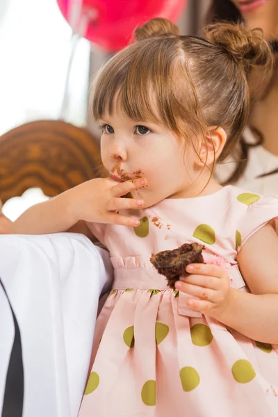 Aranyos lány enni tortát jegesedés, arcán — Stock Fotó