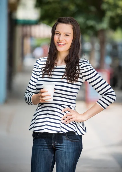 Vrouw bedrijf koffie beker buitenshuis — Stockfoto